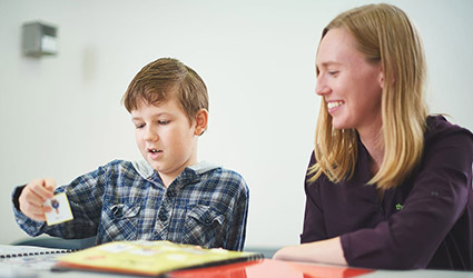 Boy picks up card as therapist looks on