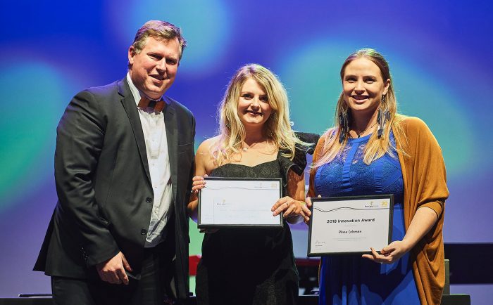 man presents awards to two women