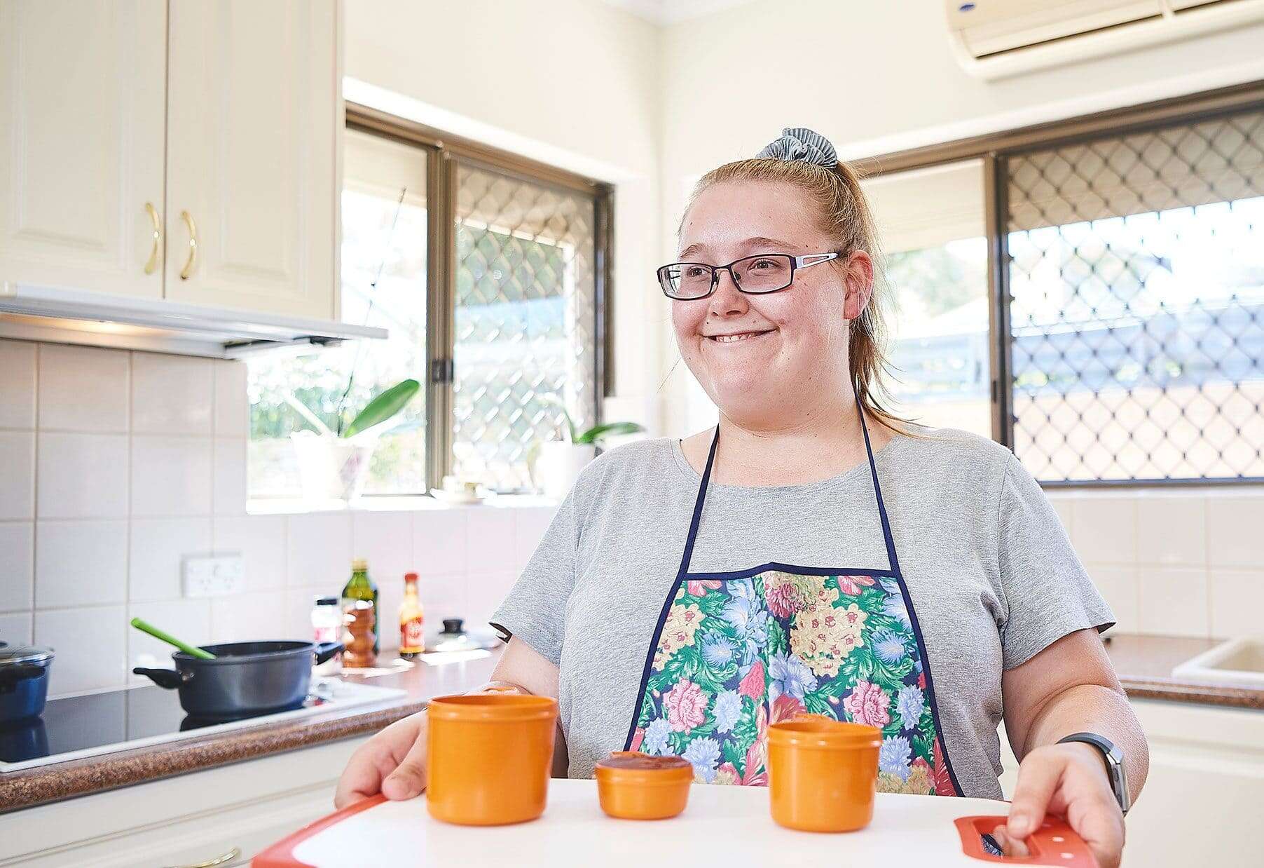 A young woman holding a tray smiling