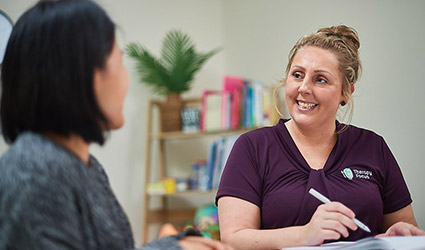 A customer and therapist talk to each other while they sit at a table