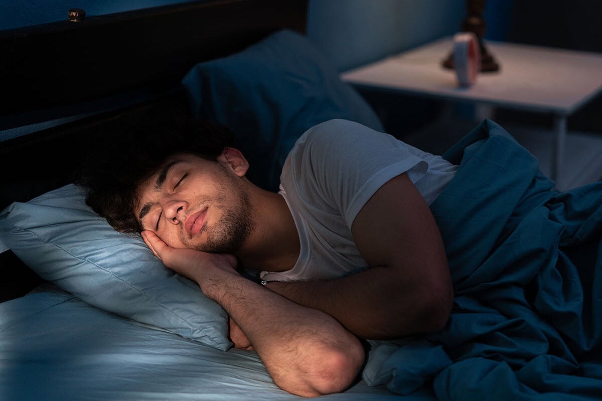 Peaceful young man sleeping in a comfortable bed